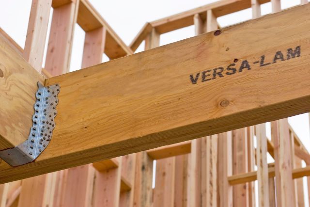 A Versa-Lam LVL beam stamped with the Versa-Lam brand, installed in a wood-framed wall with a joist hanger